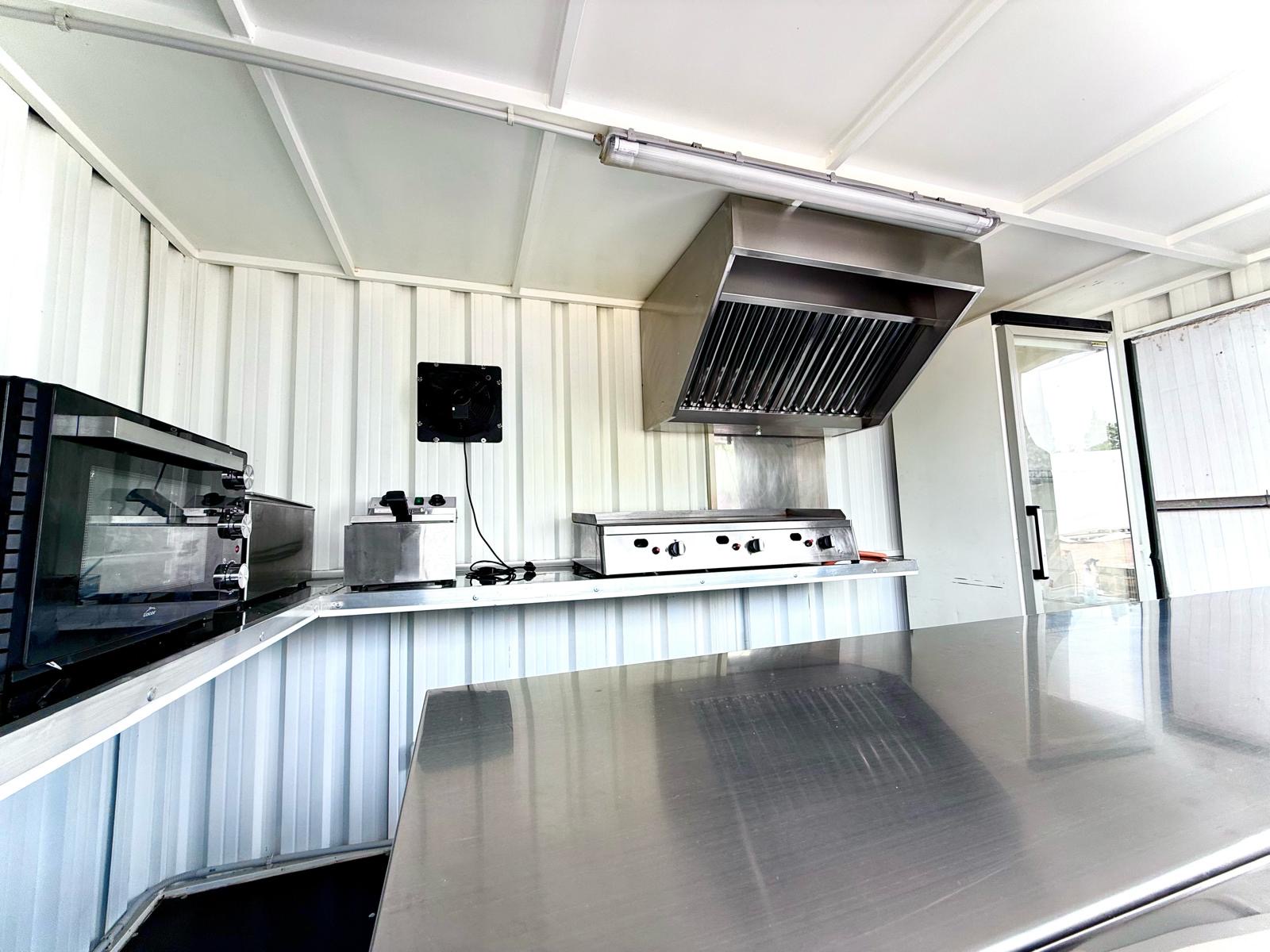 Interior de un remolque equipado con plancha, horno y campana extractora